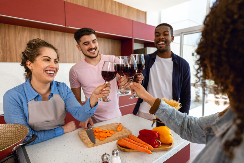 Amigos brindando com vinho enquanto cozinham 