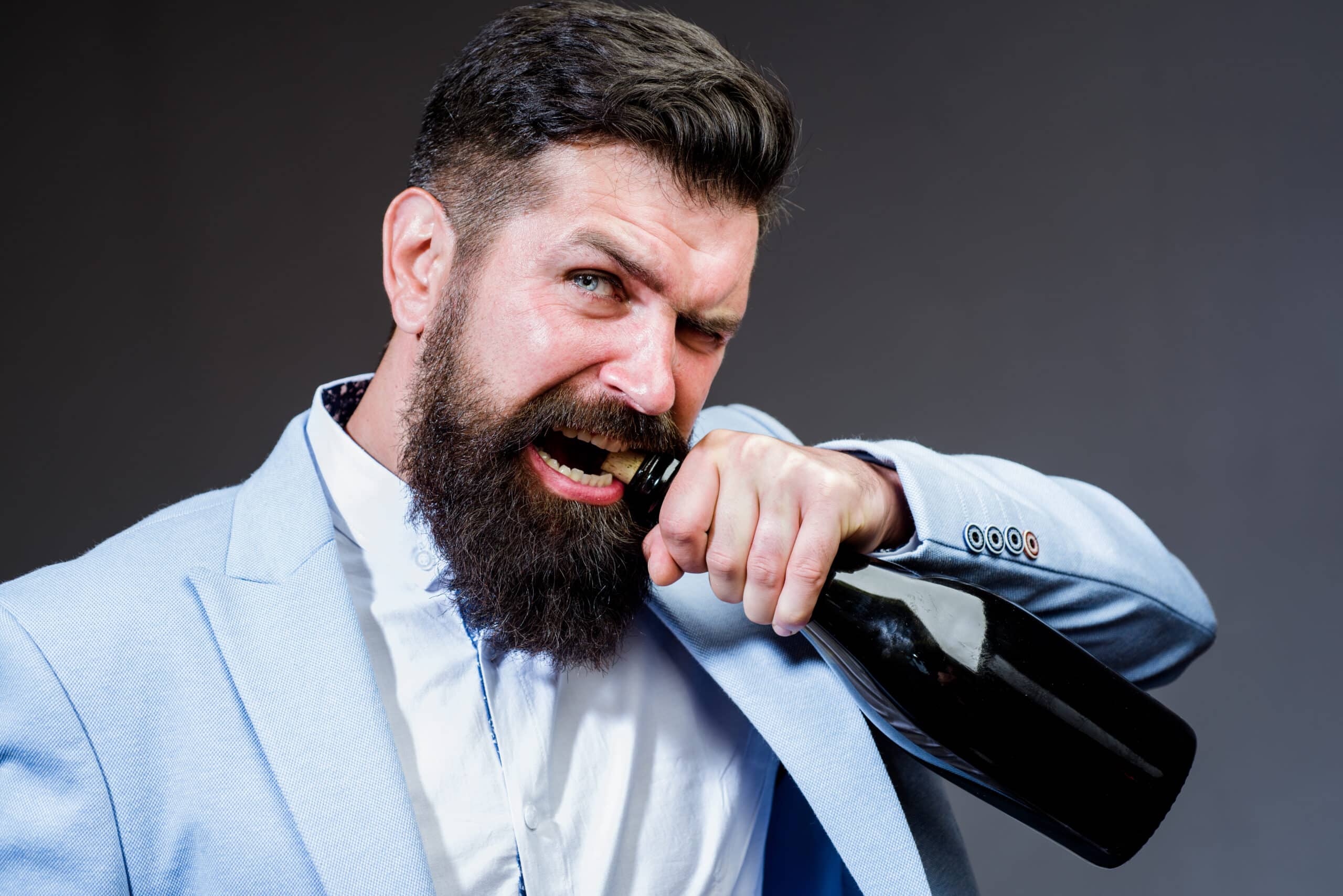 Homem tentando abrir garrafa de vinhos sem saca rolhas